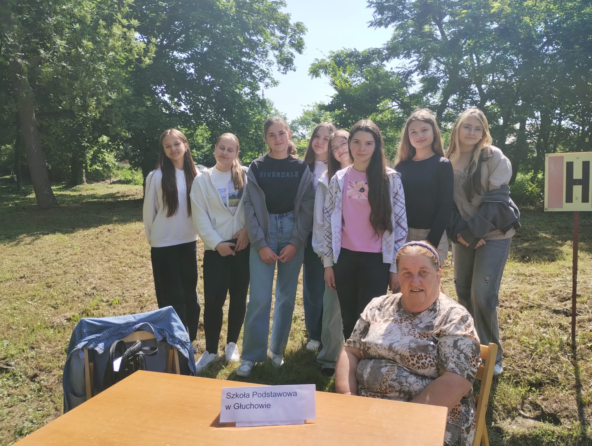 Zdjęcie grupowe, przed grupą stoi stolik z nazwą szkoły