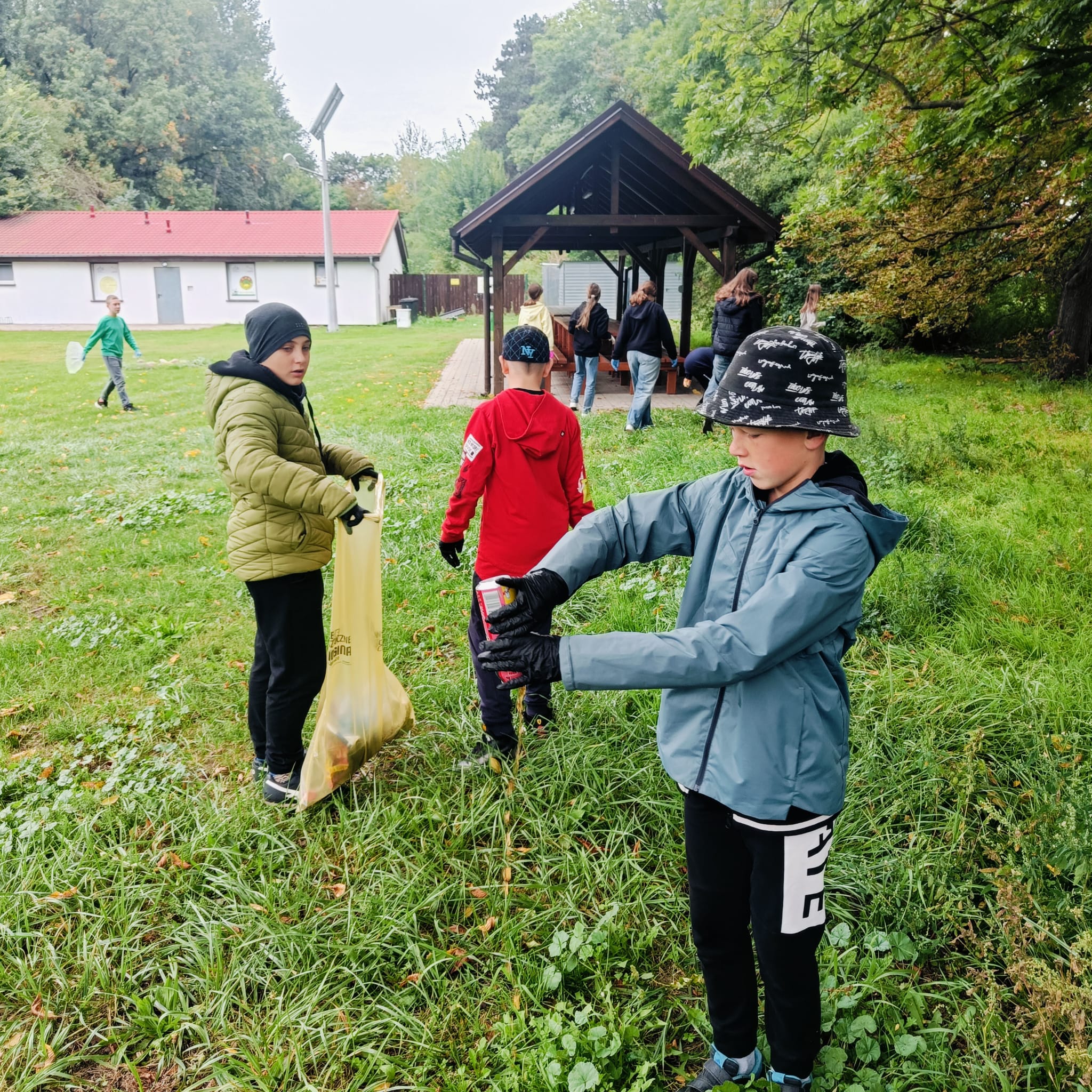 Chłopiec trzyma puszkę a drugi stoi z workiem na śmieci